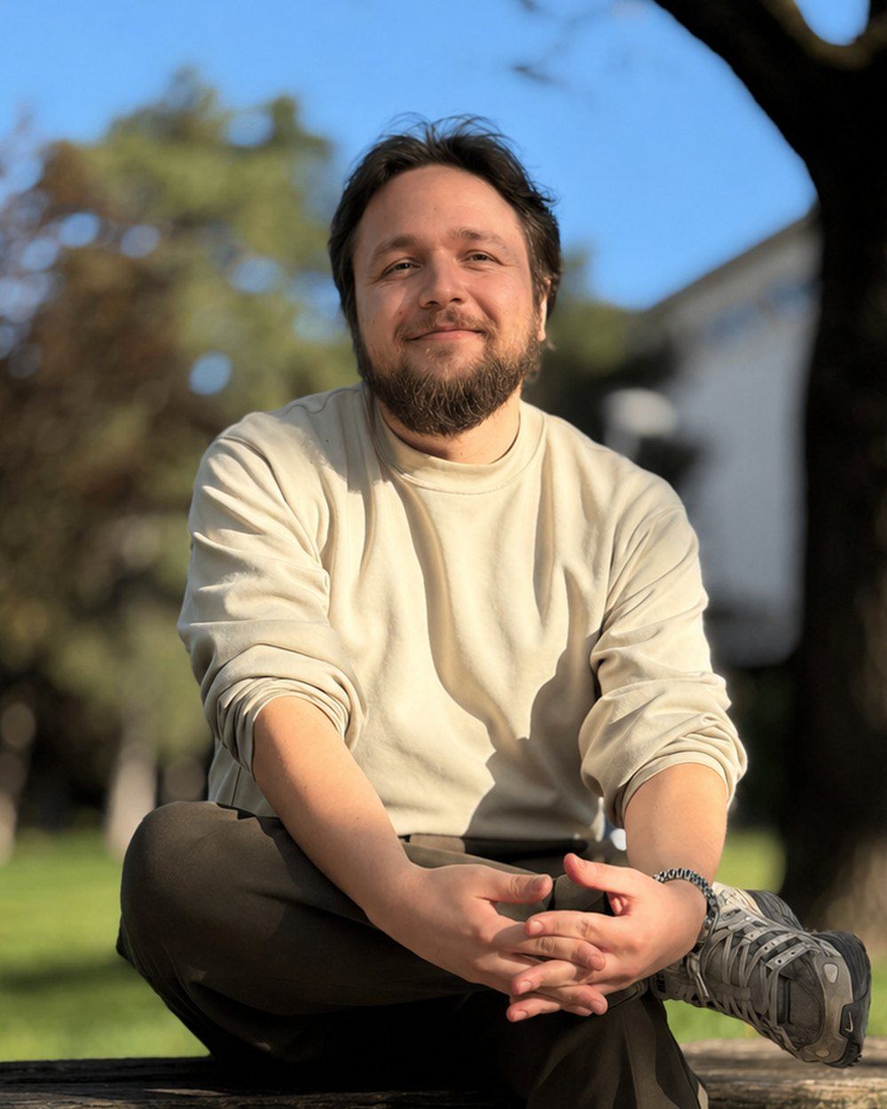 Michal Podraský sedí v parku na slunci a usmívá se.