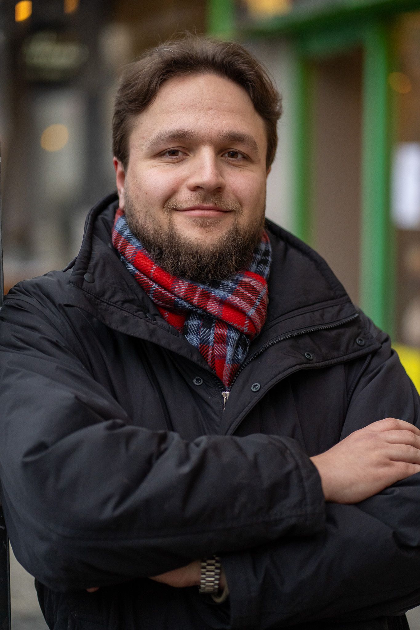Michal Podraský v zimní bundě a kostkované šále na ulici.